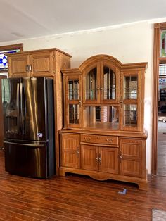 a black refrigerator freezer sitting next to a wooden china cabinet