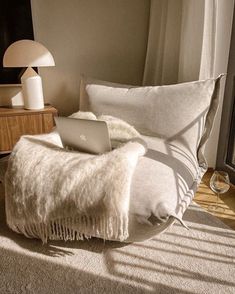 a laptop computer sitting on top of a white bed in a bedroom next to a window