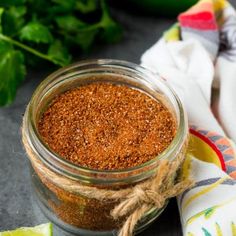 a close up of a jar of spices on a table with napkins and vegetables in the background