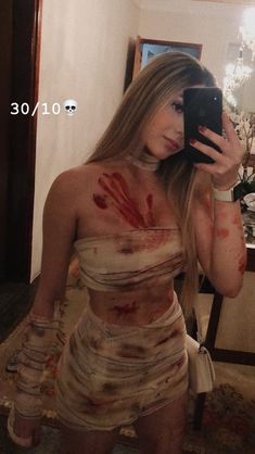 a woman is dressed up as a zombie holding a cell phone in her hand and looking at the camera