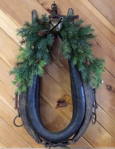 a wreath made out of two large horns hanging on a wall with pine cones and bells attached to it