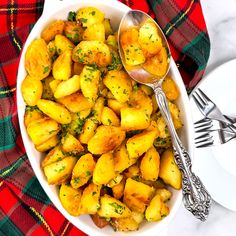 a white bowl filled with potatoes on top of a red and green plaid table cloth