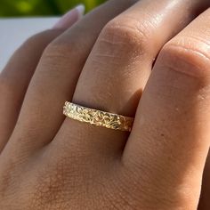 a woman's hand with a gold wedding ring on it, showing the band