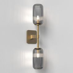 two lights that are next to each other on a white wall and one light is gold