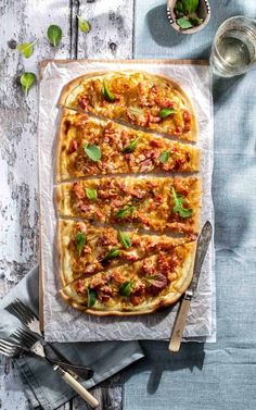 an overhead view of a pizza with meat and cheese on it, surrounded by utensils