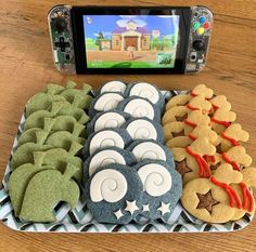 there are many cookies and pastries on the tray next to the camera phone, which is displaying an image of a house