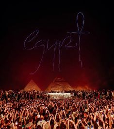 people are taking pictures with their cell phones at night in front of the pyramids