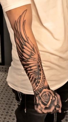 a man with a tattoo on his arm holding a rose and an angel's wings