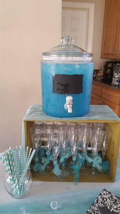 there is a blue cooler on top of the table with many glasses and straws