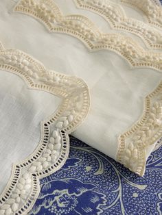 an embroidered piece of cloth on top of a blue and white tablecloth with lace