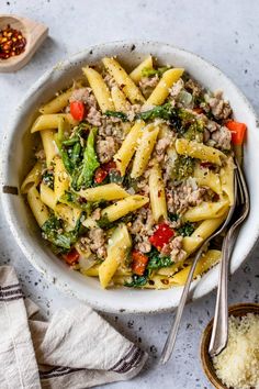 a white bowl filled with pasta, meat and veggies on top of a table