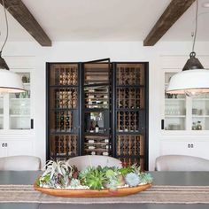 the dining room table is surrounded by black cabinets and white chairs, with succulents on top