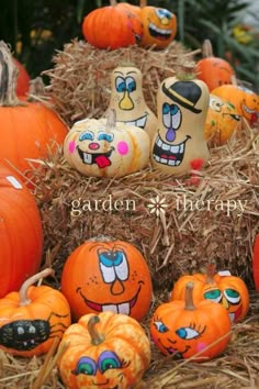 pumpkins with faces painted on them sitting in hay