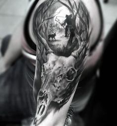 a man's arm with a deer and wolf tattoo on it, in black and white