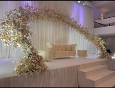 a couch sitting on top of a stage covered in flowers and greenery next to a set of stairs