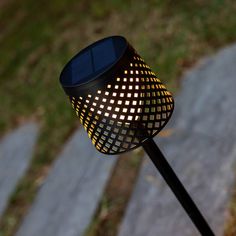 a close up of a light that is on top of a metal pole with grass in the background