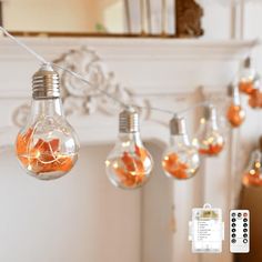 several light bulbs are hanging from a string with oranges in them and remote controls