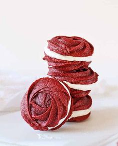 red velvet cookies stacked on top of each other with white frosting in the middle