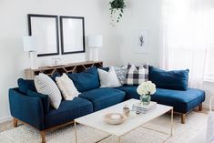 a living room with blue couches and white coffee table in front of two mirrors