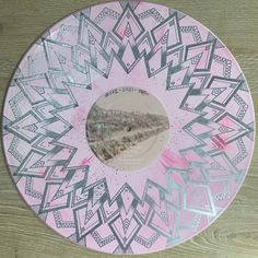 a pink and silver plate with an abstract design on the front, sitting on a wooden surface