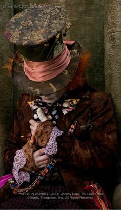 a woman sitting in a chair with a hat on her head and holding a teddy bear