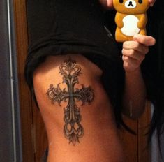 a woman with a cross tattoo on her back holding a teddy bear in her right hand