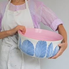 a woman in an apron holding a pink and white bowl