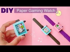 a person is holding a watch and playing with some paper crafting toys on a pink background