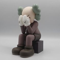 a figurine sitting on top of a black box holding his hands to his face