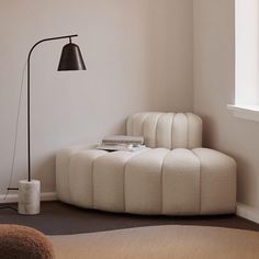 a room with a round bed and a lamp on the floor next to a window