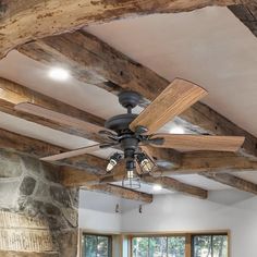 a living room with a ceiling fan and stone fireplace