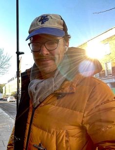 a man wearing glasses and a hat is standing on the street