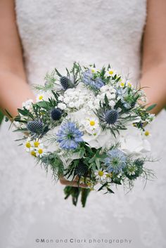 a bride holding a bouquet of white and blue flowers