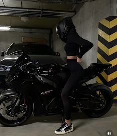 a woman is standing next to a motorcycle in a parking garage with a helmet on her head