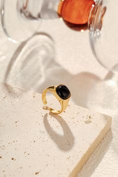 A symbol of protection and quiet confidence, the "Nocturne" Black Onyx Square Ring carries the strength of the night within its bold design. The natural black onyx, known for grounding energy and shielding its wearer from negativity, sits at the heart of this striking piece. Encased in 18k Gold Vermeil over sterling silver, its clean, angular lines speak to modern elegance, while the deep, lustrous stone evokes a sense of mystery and resilience. Materials: Natural black onyx, framed in 18k Gold Black Polished Finish Promise Ring, Black Crystal Gemstone Ring For Gift, Black Crystal Ring With Gemstone For Gift, Adjustable Black Enamel Onyx Rings, Adjustable Onyx Rings With Black Enamel, Minimalist Black Onyx Signet Ring, Black Onyx Rings With Polished Finish, Black Signet Ring With Polished Finish For Promise, Black Spiritual Rings With Gemstone