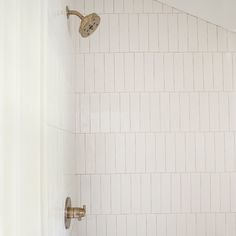 a bathroom with a toilet, shower head and white tile on the wall behind it