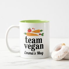 a white and green coffee mug sitting next to a donut