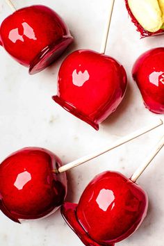 several red candy apples sitting on top of a white counter next to an apple slice