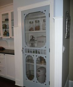 an open pantry door in a kitchen with white cabinets