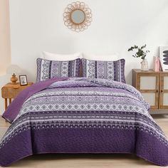 a bed with purple and white bedspread in a room