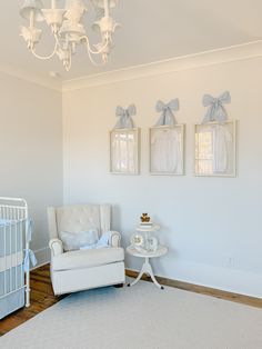 a baby's room with a white crib, chair and chandelier