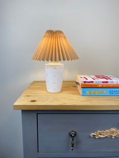 a lamp sitting on top of a dresser next to books