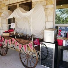 an old fashioned wagon is decorated with pink and white fabric, along with other items