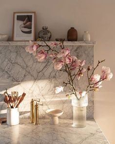 a marble counter top with flowers in vases on it and other items sitting on the counter