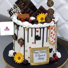 a decorated birthday cake with sunflowers and chocolate bars on the top, sitting on a table