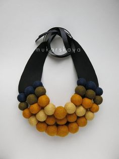 a black and yellow necklace with pom - poms hanging from it's side