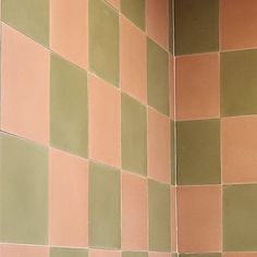 a white toilet sitting next to a green tiled wall