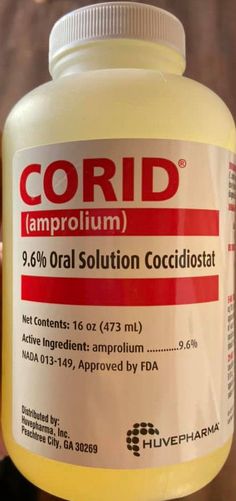 a hand holding a bottle of coridd amprolium in it's left hand