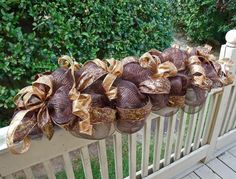 some brown and gold ribbons are hanging on a rail near the fence in front of bushes