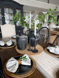 the table is set with black and white dishes, candles, napkins and flowers